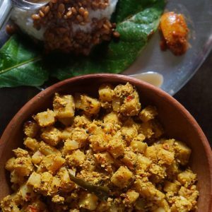 Banana stem Ajadina in a clay bowl, with rice and horse gram saar in the background.