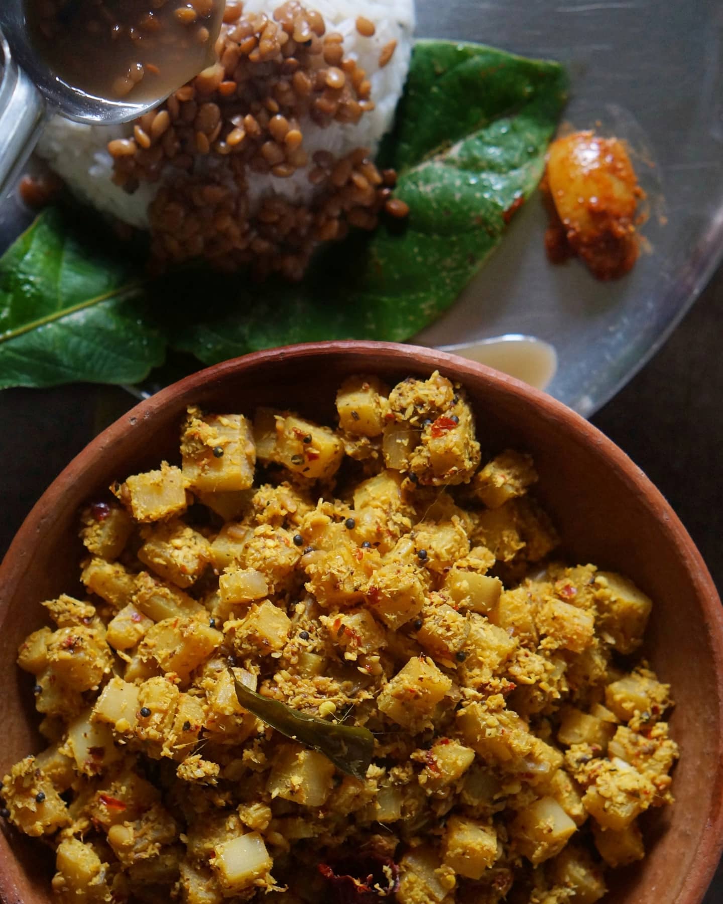 Banana stem Ajadina in a clay bowl, with rice and horse gram saar in the background.