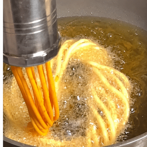 Thick Khara Kaddi strands pressed into hot coconut oil