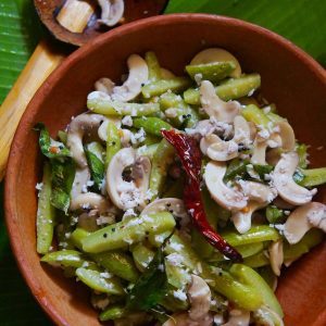 Ivy gourd and tender cashew Upkari with grated coconut, mustard seeds, red chilli and curry leaves in a clay bowl.