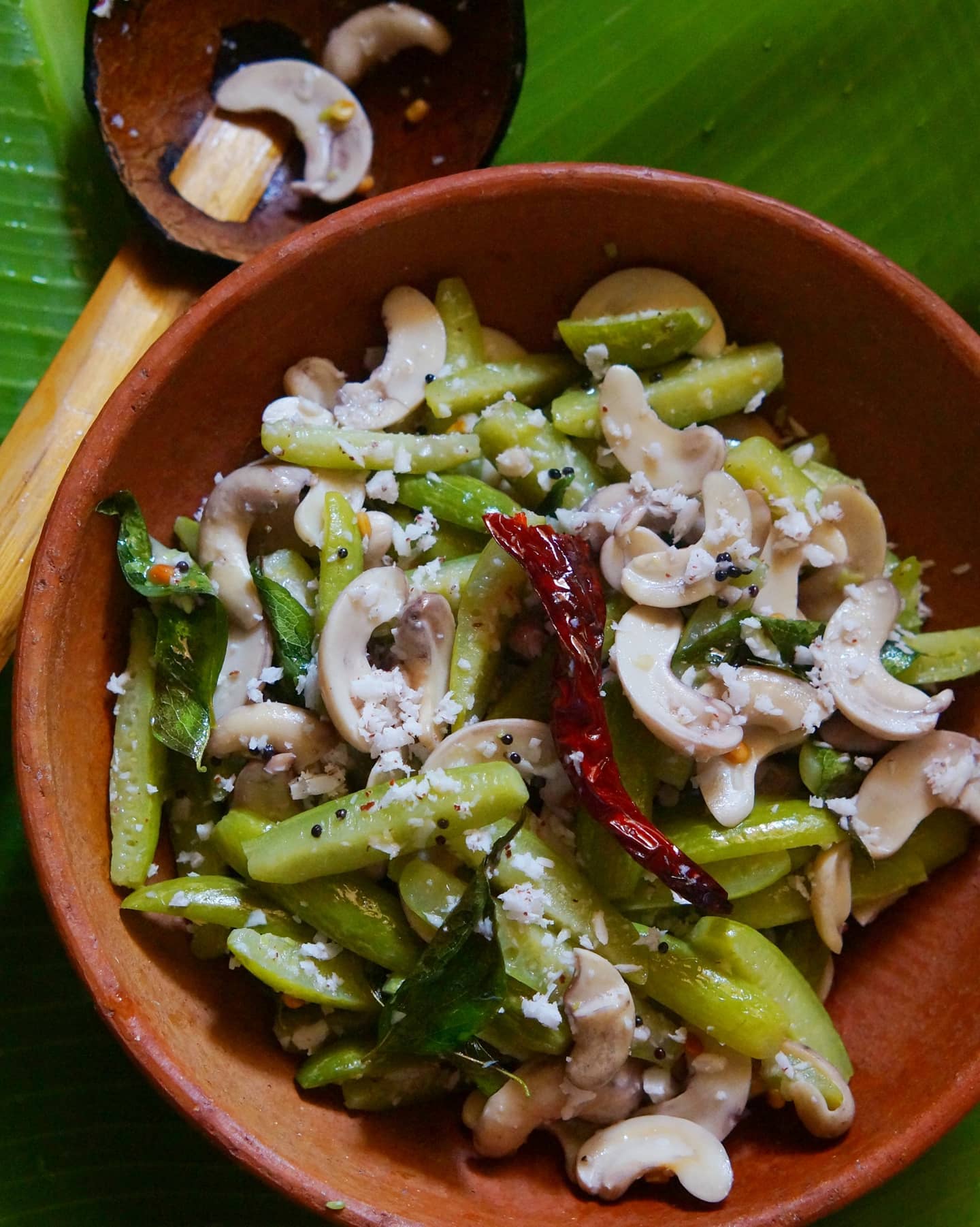 Ivy gourd and tender cashew Upkari with grated coconut, mustard seeds, red chilli and curry leaves in a clay bowl.