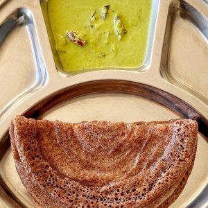 Ragi dose served with green kothambari chutney on a stainless steel plate