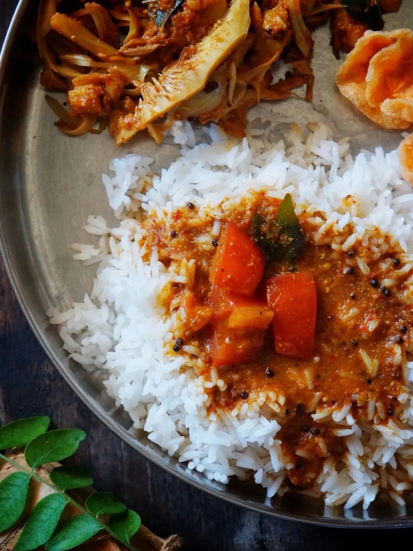 Temple-style tomato Saar poured over white rice on a steel meal plate